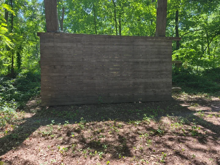 Verwitterte Holzwand einer Kletterwald-Plattform zwischen Bäumen